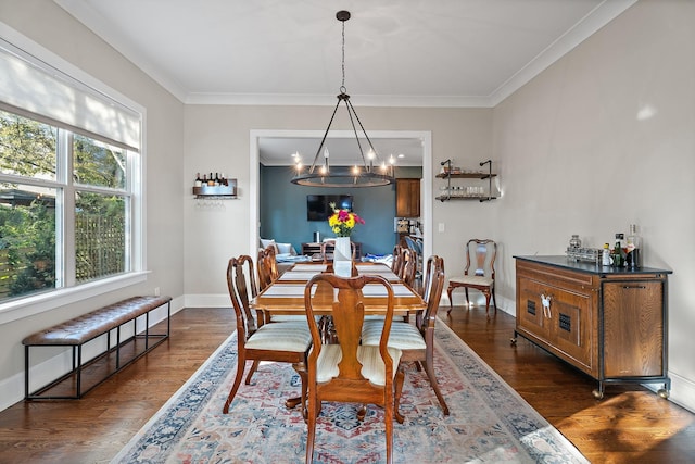 dining space featuring dark wood-type flooring, a notable chandelier, and ornamental molding