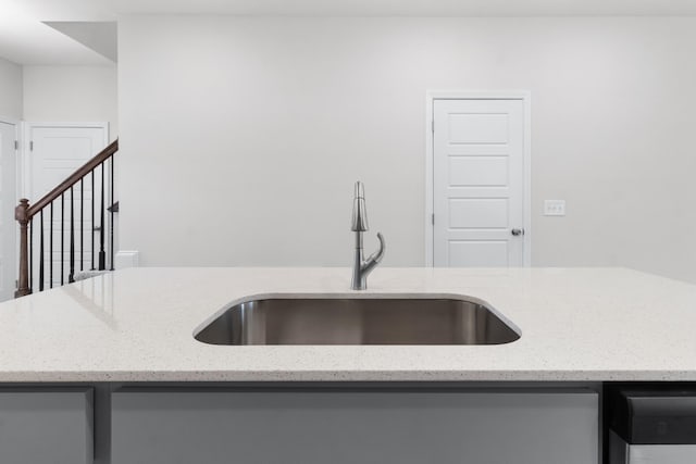 kitchen featuring light stone counters and sink