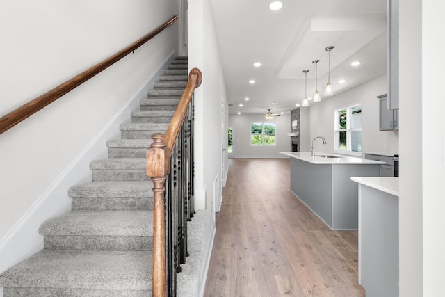 stairs featuring wood-type flooring, ceiling fan, and sink