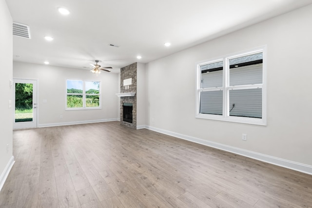 unfurnished living room featuring a stone fireplace, ceiling fan, and light wood-type flooring