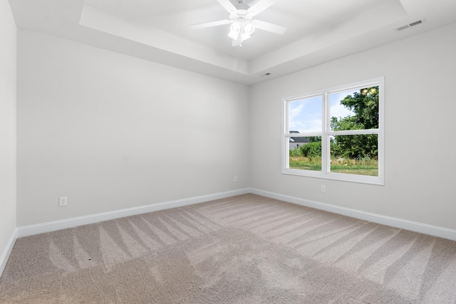 carpeted empty room featuring a tray ceiling and ceiling fan