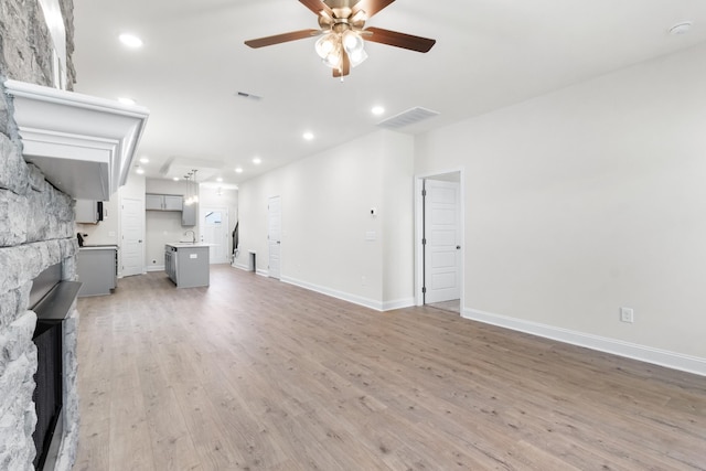 unfurnished living room with a fireplace, hardwood / wood-style flooring, and ceiling fan