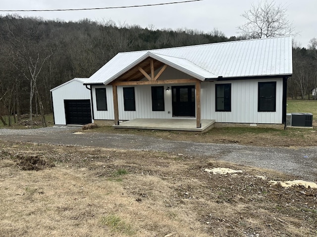 view of front of property with central air condition unit, an outbuilding, covered porch, and a garage