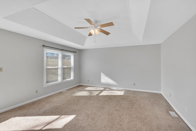 spare room featuring carpet, a tray ceiling, and ceiling fan