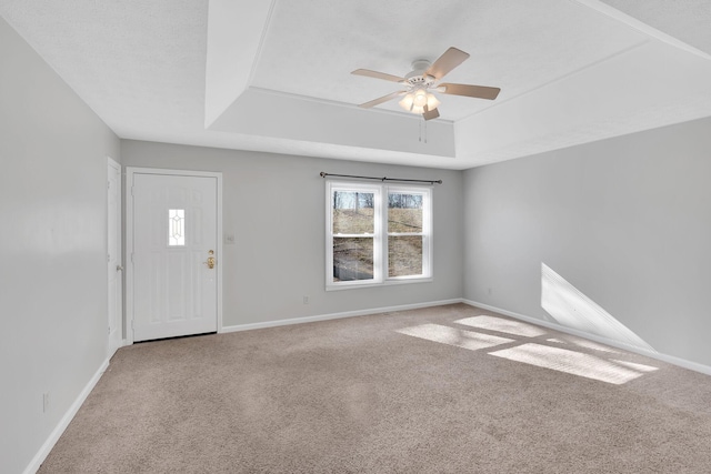 interior space featuring a raised ceiling and ceiling fan