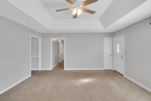 carpeted empty room with ceiling fan and a tray ceiling