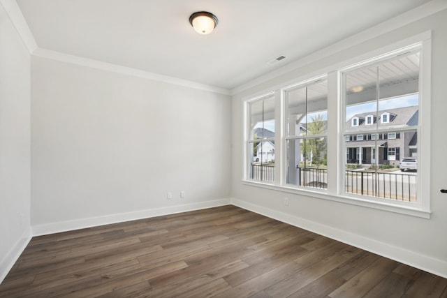 empty room with plenty of natural light, ornamental molding, and dark wood-type flooring