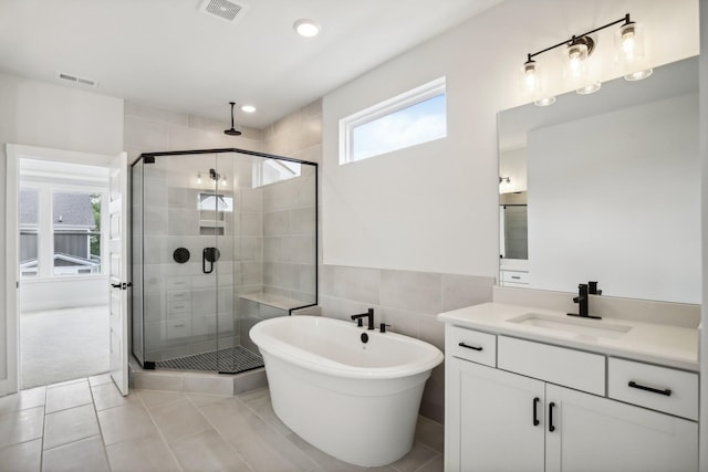 bathroom featuring tile patterned flooring, vanity, tile walls, and plus walk in shower