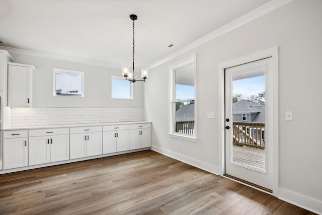 unfurnished dining area with light hardwood / wood-style flooring, a chandelier, and ornamental molding