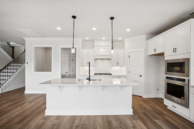 kitchen with built in microwave, a kitchen island with sink, sink, and oven