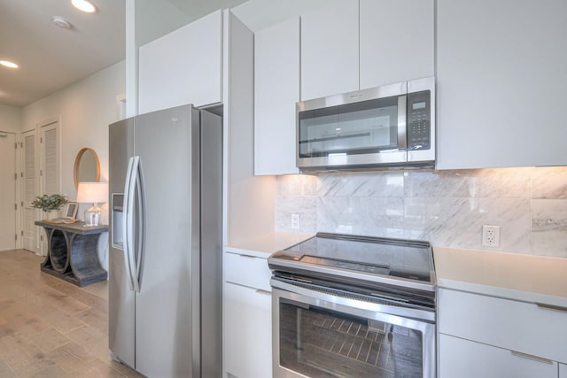 kitchen featuring backsplash, white cabinetry, stainless steel appliances, and light hardwood / wood-style flooring