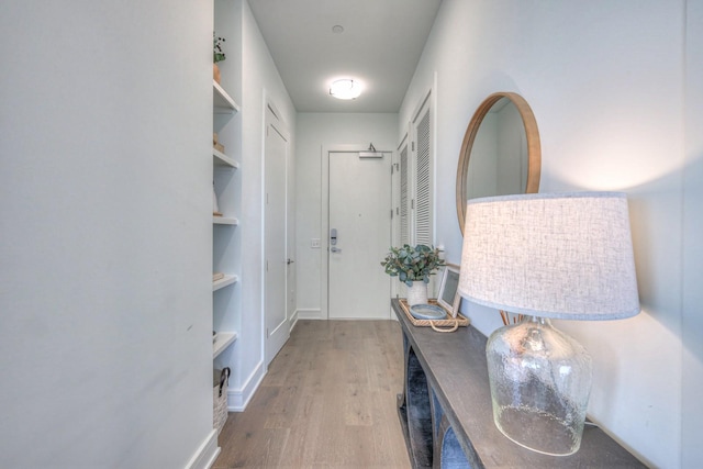 corridor featuring hardwood / wood-style floors and built in shelves