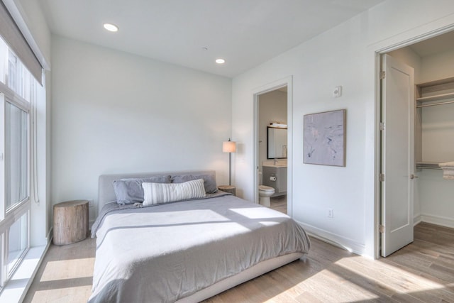 bedroom featuring a spacious closet, a closet, light hardwood / wood-style floors, and ensuite bath