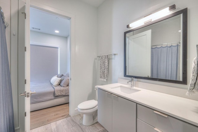 bathroom with hardwood / wood-style floors, vanity, and toilet