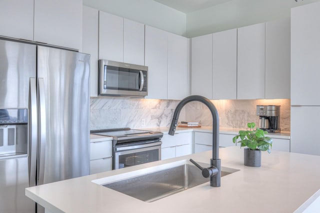 kitchen with decorative backsplash, appliances with stainless steel finishes, sink, white cabinets, and a kitchen island