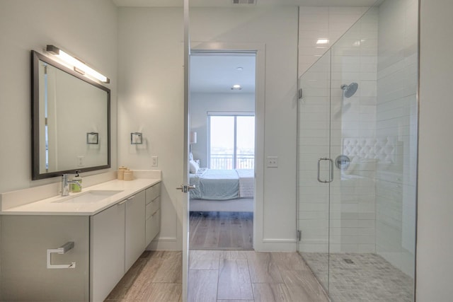 bathroom featuring a shower with door and vanity