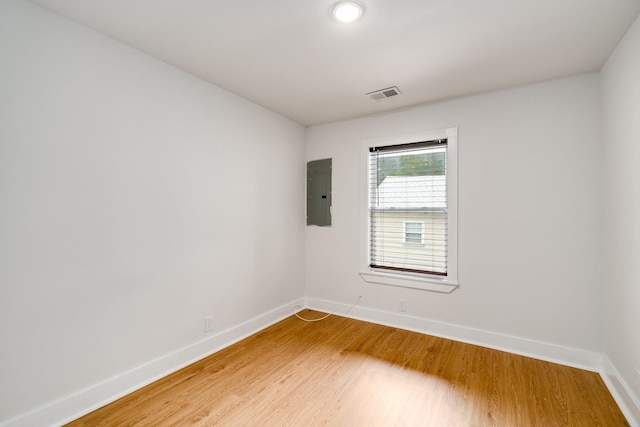 empty room featuring electric panel and hardwood / wood-style flooring