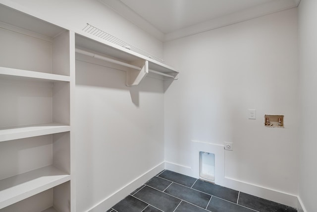 laundry room featuring hookup for an electric dryer, hookup for a washing machine, dark tile patterned flooring, and ornamental molding