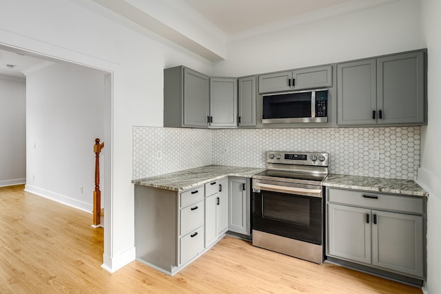 kitchen featuring stainless steel appliances, light stone counters, tasteful backsplash, and gray cabinetry