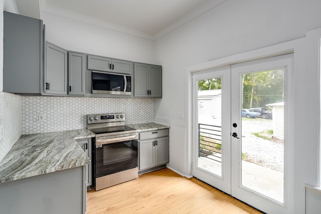 kitchen with gray cabinetry, decorative backsplash, light stone countertops, and appliances with stainless steel finishes