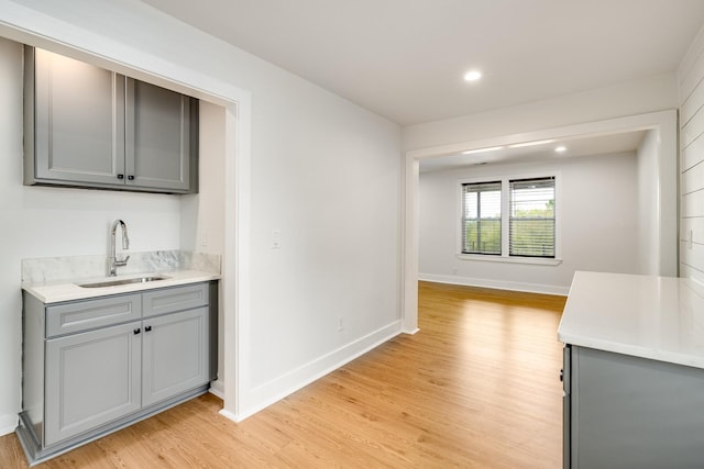 kitchen with gray cabinetry, light wood-type flooring, and sink