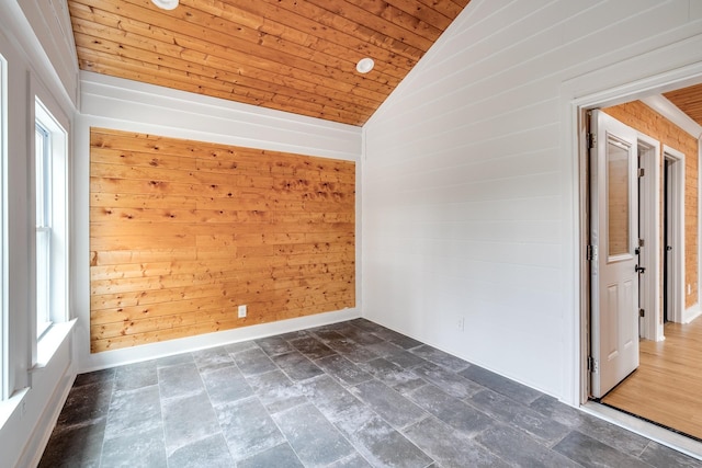 empty room with lofted ceiling, wood ceiling, and wooden walls