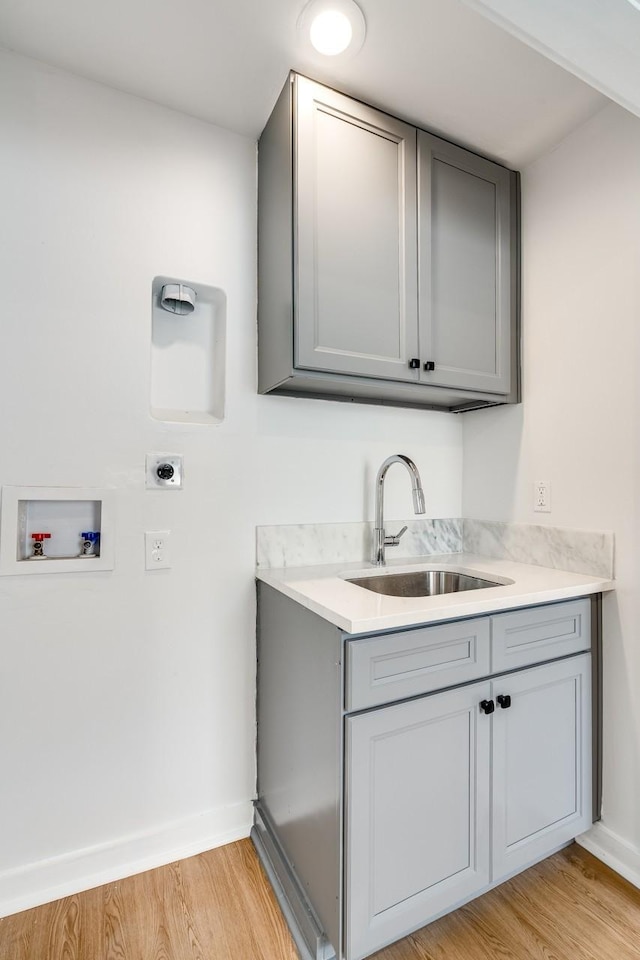 washroom with cabinets, hookup for a washing machine, electric dryer hookup, sink, and light hardwood / wood-style flooring