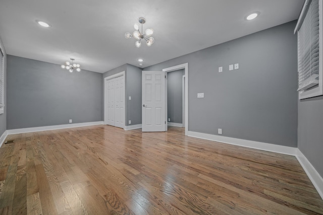 unfurnished room with hardwood / wood-style floors and a notable chandelier