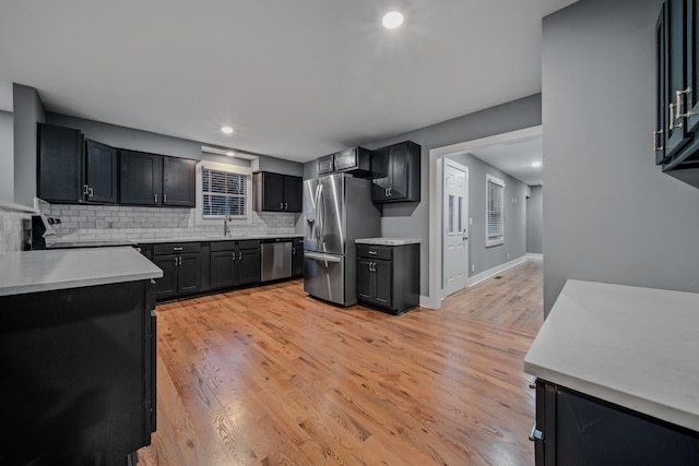 kitchen with backsplash, sink, light wood-type flooring, and stainless steel appliances