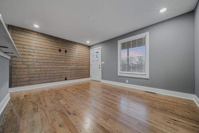 unfurnished room featuring hardwood / wood-style flooring and wooden walls