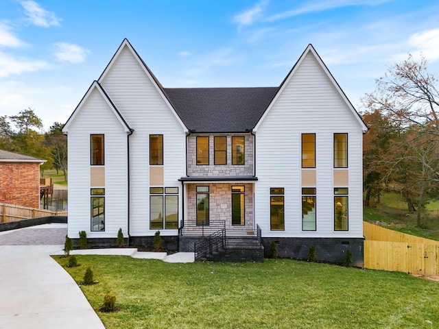 modern inspired farmhouse featuring stone siding, a front lawn, and fence