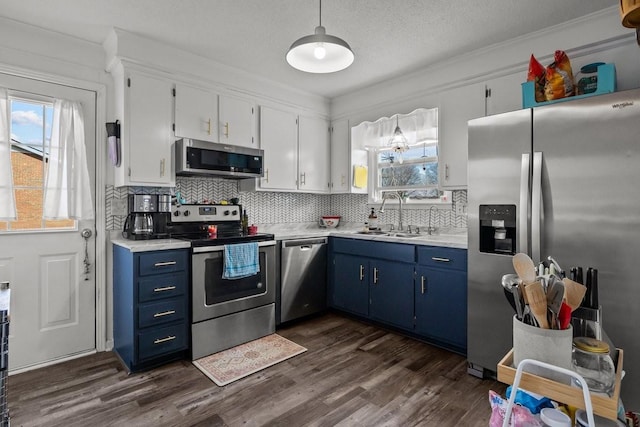 kitchen featuring sink, blue cabinets, backsplash, white cabinets, and appliances with stainless steel finishes