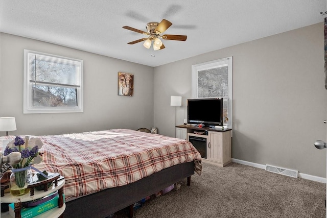 carpeted bedroom featuring ceiling fan and a textured ceiling