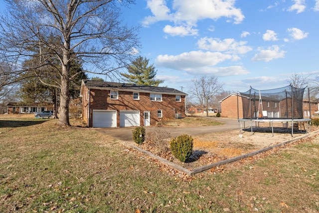 view of yard with a garage and a trampoline