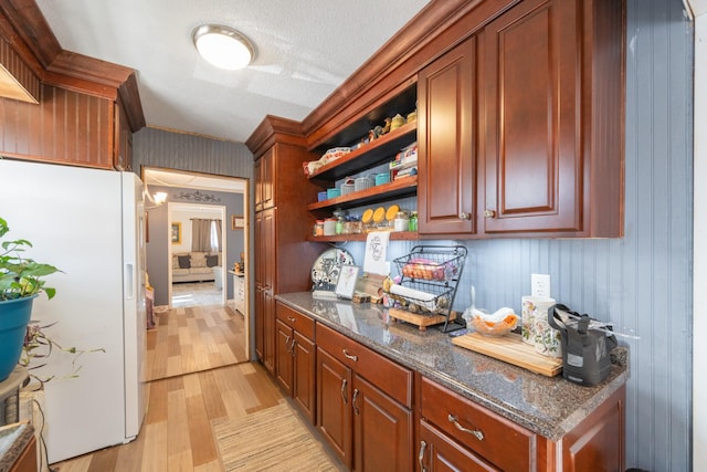 bar featuring white refrigerator, dark stone countertops, a textured ceiling, and light hardwood / wood-style flooring