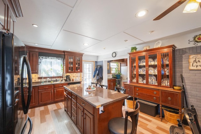 kitchen with backsplash, black refrigerator, a kitchen island, and plenty of natural light