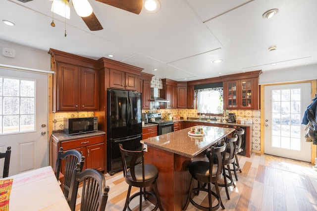 kitchen with black appliances, a center island, and a healthy amount of sunlight