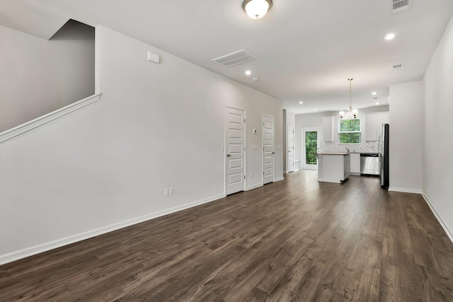 unfurnished living room featuring a notable chandelier and dark hardwood / wood-style floors