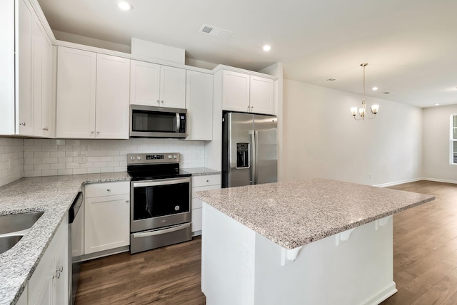 kitchen with pendant lighting, white cabinets, stainless steel appliances, and a notable chandelier