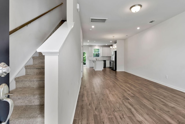 staircase with a chandelier and hardwood / wood-style flooring