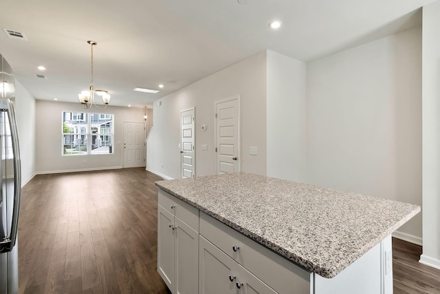 kitchen with white cabinets, a notable chandelier, pendant lighting, and light stone counters