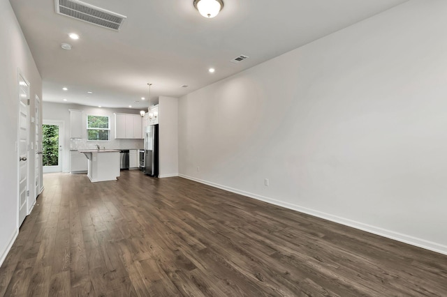 unfurnished living room featuring dark hardwood / wood-style flooring, a chandelier, and sink