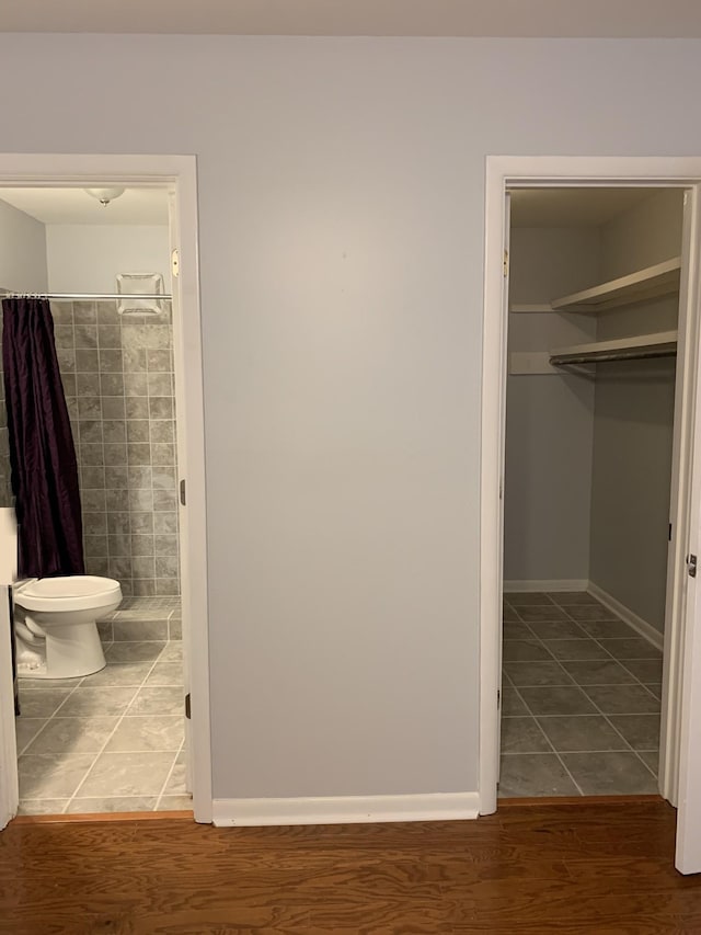 bathroom with wood-type flooring, toilet, and curtained shower