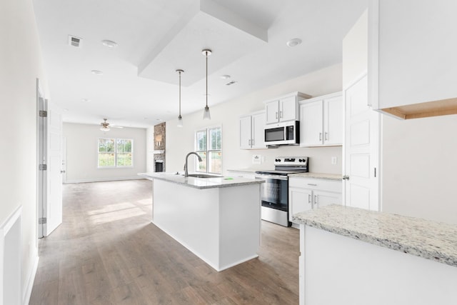 kitchen featuring stainless steel appliances, ceiling fan, sink, white cabinets, and an island with sink