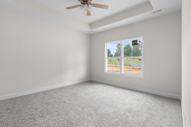 carpeted empty room with a tray ceiling and ceiling fan