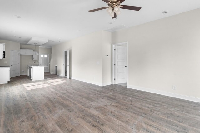 unfurnished living room with dark hardwood / wood-style floors and ceiling fan