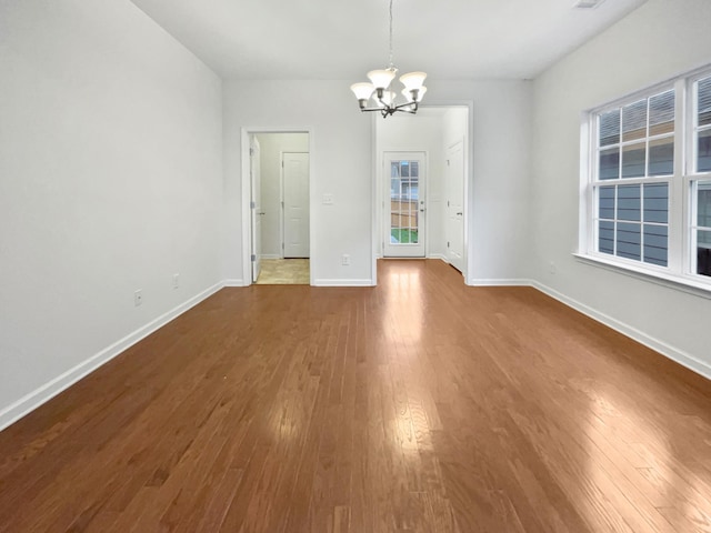 spare room featuring a chandelier and hardwood / wood-style flooring