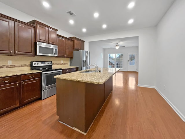 kitchen with a kitchen island with sink, sink, light hardwood / wood-style flooring, ceiling fan, and appliances with stainless steel finishes