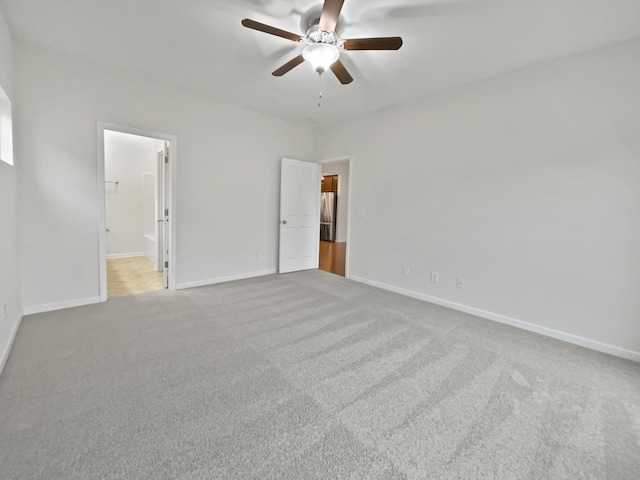 unfurnished bedroom with ensuite bathroom, ceiling fan, a spacious closet, light colored carpet, and a closet