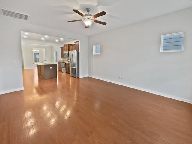 unfurnished living room featuring light hardwood / wood-style floors, ceiling fan, and sink